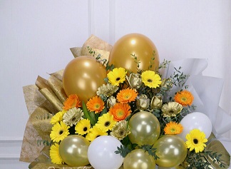 20 gerberas yellow orange with 6 gold white air balloons and leaves gold wrapping